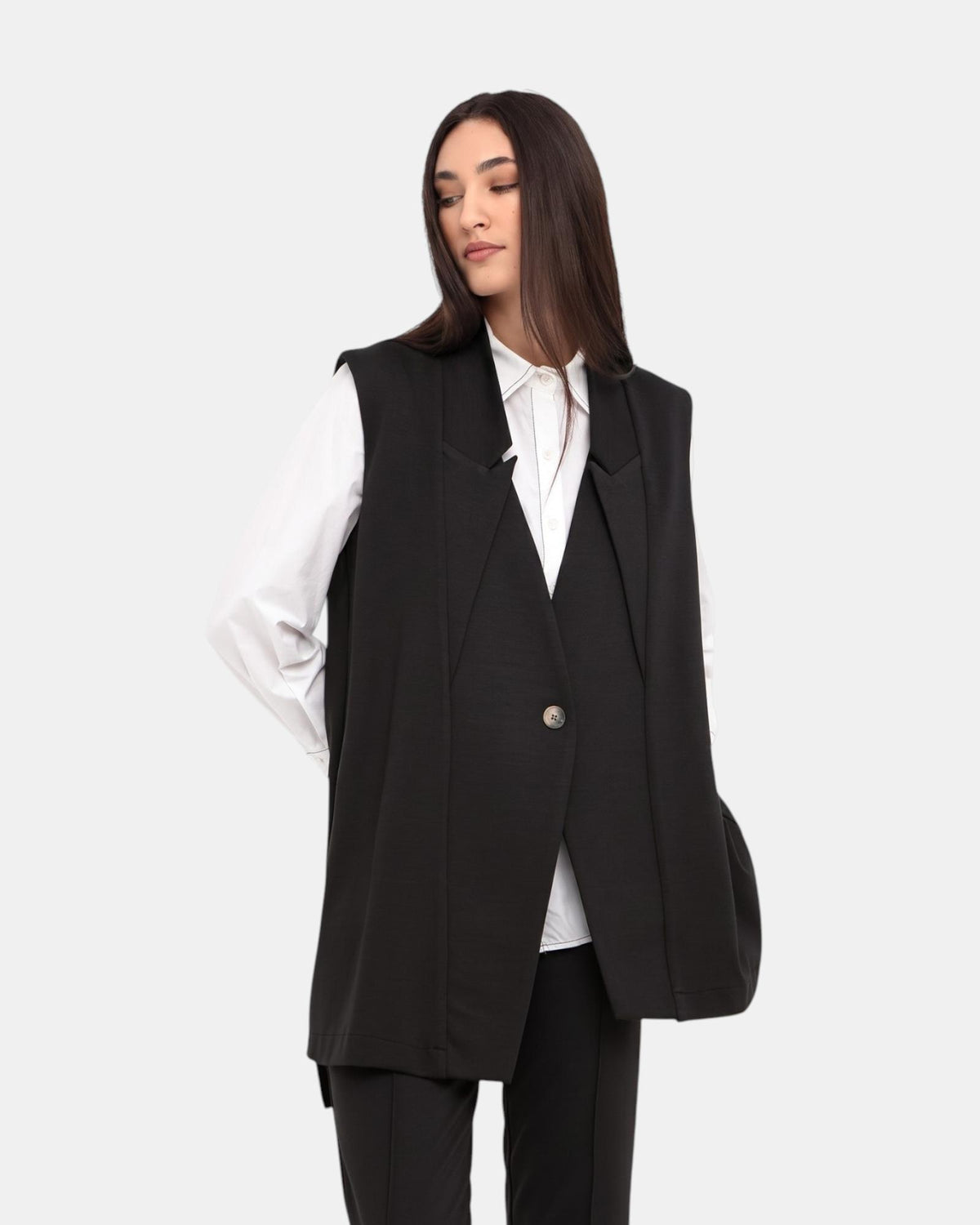 Modell trägt eine schwarze ärmellose OZAI N KÜ GWEN-Weste mit langer Silhouette und Knopfverschluss von LEEZZA