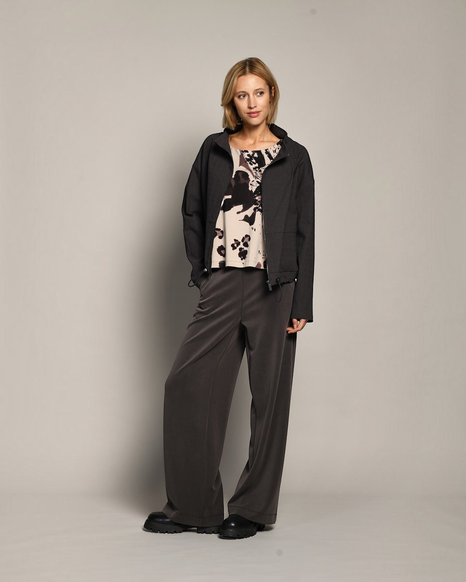 Model wearing LEEZZA AMBER & MOON DORY wide-leg scuba trousers in dark grey with a stretch waistband and side pockets.